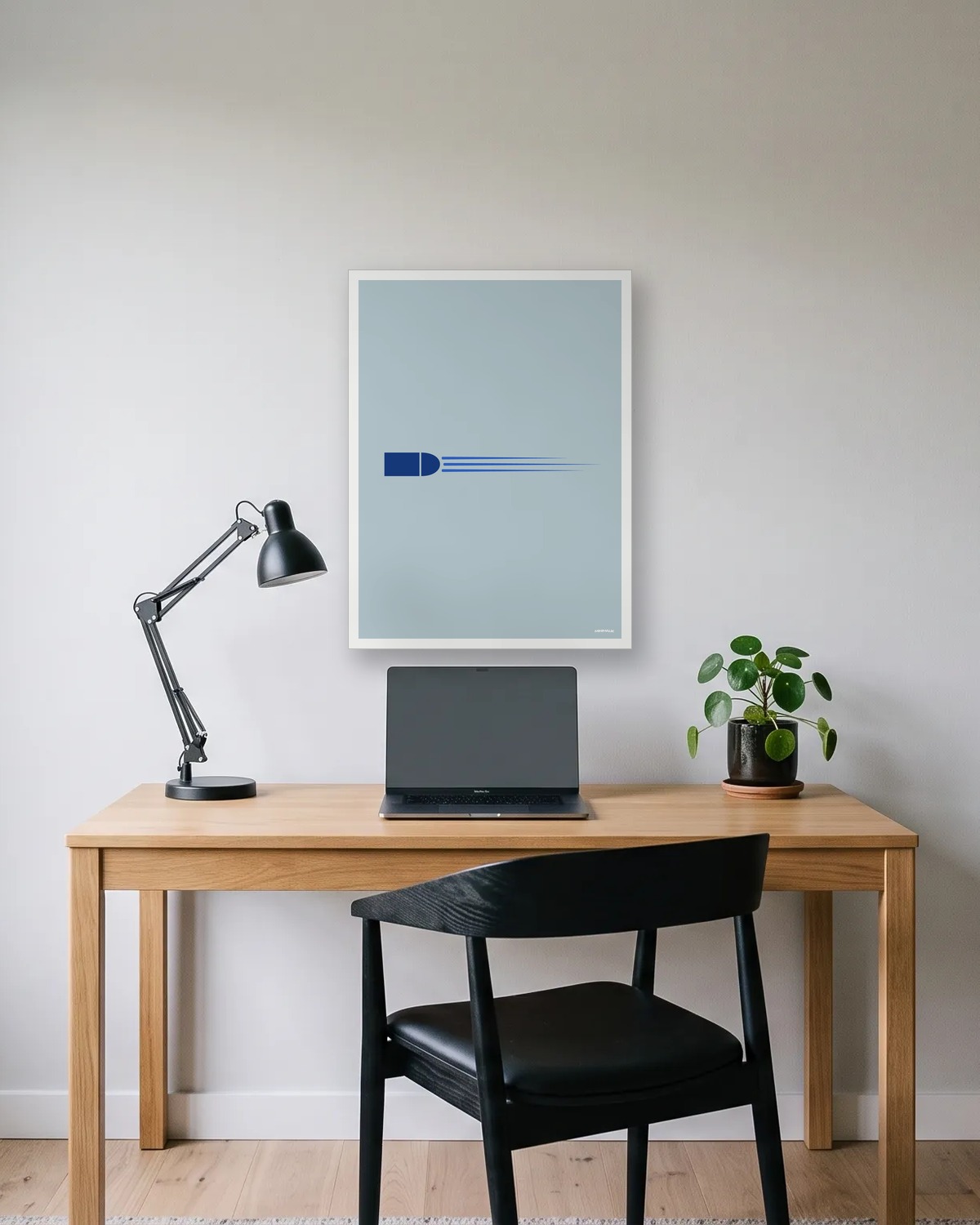 Affiche minimaliste gris bleu, une balle bleue et sa traînée, encadrée en blanc au-dessus d'un bureau en bois et d'une lampe noire